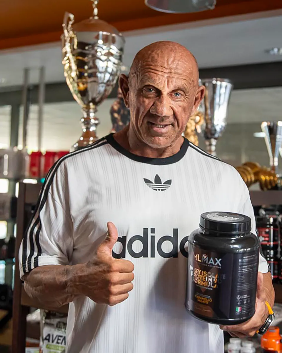 Marco Lucacci nel suo negozio, davanti ai trofei, con un barattolo MLMAX Whey Isolate Protein 90
