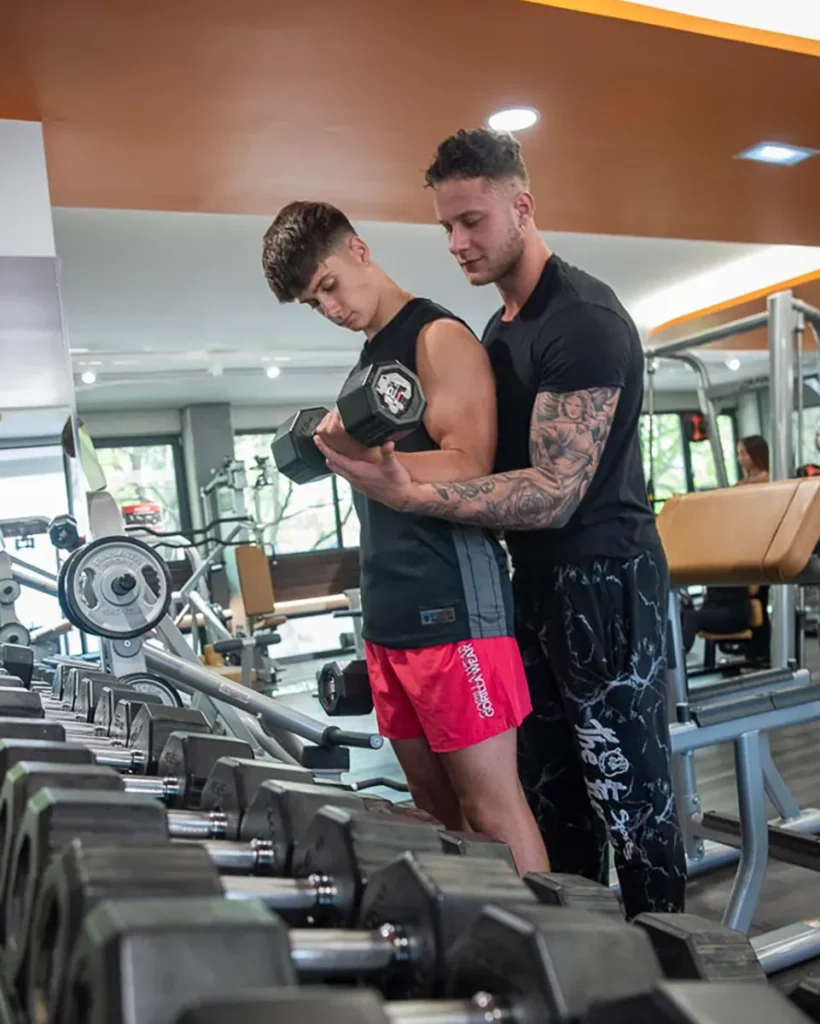 Niccolò Lucacci segue un atleta durante un curl con manubrio in sala pesi